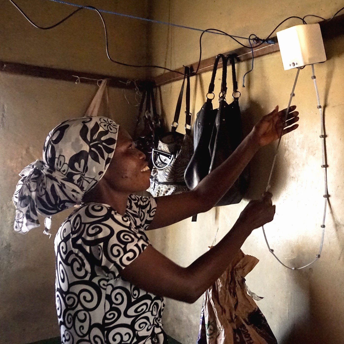 African woman pulling on a cord of nowlight – green off-grid light developed by startup Deciwatt.